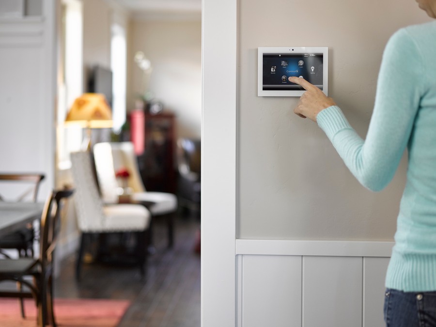 a woman wearing a sweater using a wall-mounted control panel