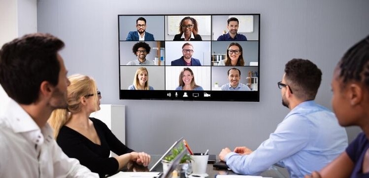 A team in a boardroom utilizing commercial audio-video solutions for a video conference call with other employees.