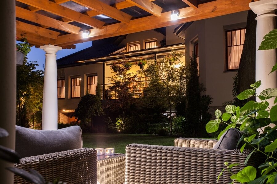 A backyard entertainment space at night with outdoor lighting and seating.