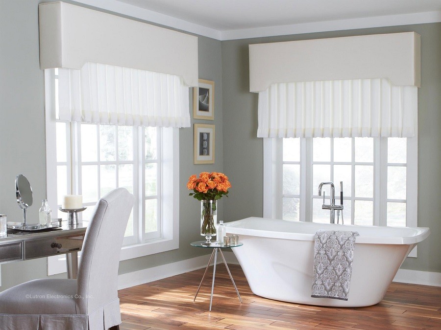 An elegant bathroom with a freestanding tub is framed by sophisticated custom window treatments.   